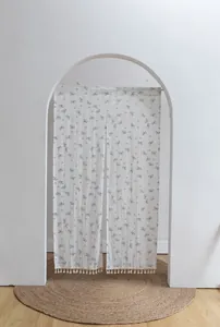 Detailed view of the delicate floral pattern and tassel fringe on a white door curtain