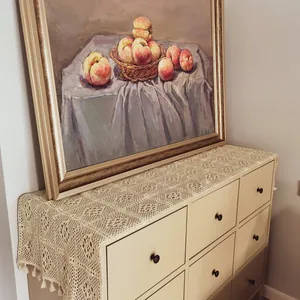 Detail view of a vintage cream hollow lace table runner on a wooden storage cabinet