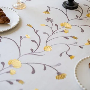 Close-up of yellow floral embroidery on a white linen tablecloth for dining decor