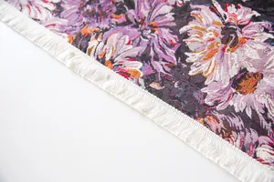 Close-up detail of high-density purple floral tablecloth with delicate white fringe
