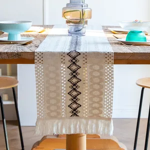 Gros plan d'un chemin de table bohème en coton tissé avec franges et motifs géométriques.
