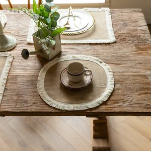Round jute placemat with white fringe detail on a rustic wooden table context.