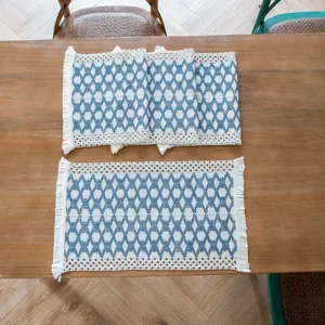 Detailed view of woven cotton linen placemats with blue geometric patterns and fringes