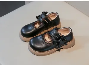Detalle de los bordes con volantes y lazo en zapatos Mary Jane negros de niña