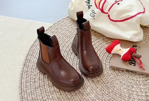 Detail van donkerbruine Chelsea boots met plateauzool op een geweven vloerkleed