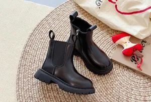 Detailopname van zwarte platform Chelsea boots op een geweven mat met decoratieve rekwisieten.