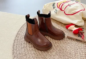 Detail van bruine leren Chelsea boots met dikke zolen op een geweven mat