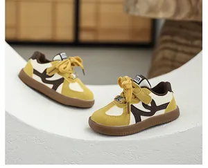 Detailed view of yellow and brown toddler German trainers with soft soles on a white stand