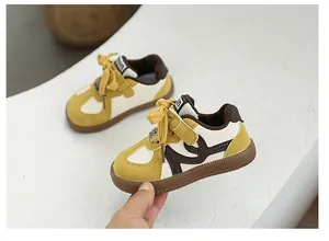 Detail of yellow and brown children's sneakers with soft sole and trainer design.