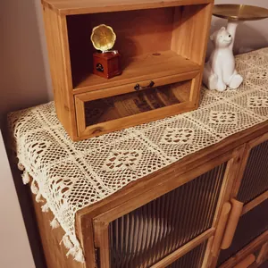 Detailed macro view of handmade vintage white lace crochet table runner with tassels.