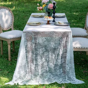 Elegant white floral lace tablecloth elegantly draped over a table in a lush garden setting