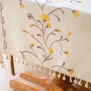 Detail view of rustic embroidered floral tablecloth with elegant tassel fringe