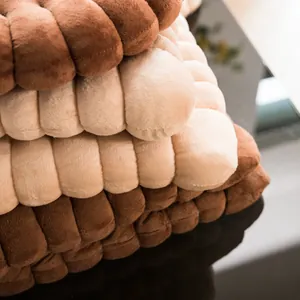 Close-up detail of soft plush biscuit-shaped floor cushions in natural earth-tone colors