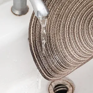 Washing a durable round woven placemat under a running faucet in the kitchen sink
