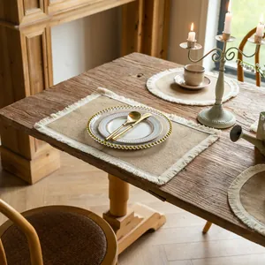 Detail of vintage farmhouse jute placemats with white fringe on a rustic wooden table