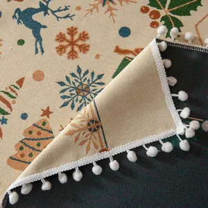 Dettaglio tovaglia jacquard natalizia con motivi festivi e bordo di pompon bianchi