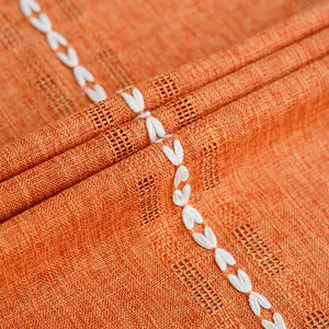 Close-up macro view of burnt orange woven curtain fabric with white leaf embroidery details