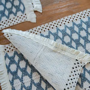 Close-up of woven cotton linen placemat with blue geometric pattern and fringe details.