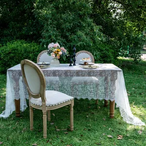 Detailed view of elegant white lace tablecloth with floral patterns in garden setting