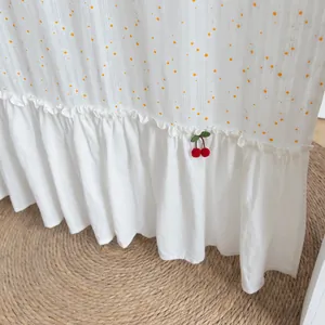 Close-up view of a white cotton curtain featuring a ruffled hem and red cherry decoration