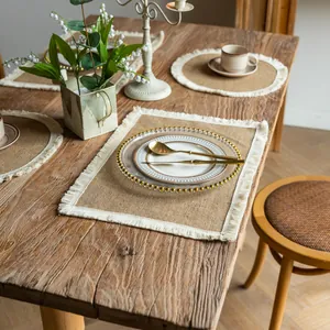 Detail view of rustic jute placemats with fringe on a wooden dining table setting.