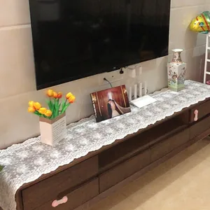Primer plano del camino de mesa de encaje floral francés blanco en mueble oscuro.