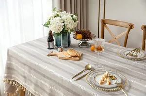 Detail view of rustic linen tablecloth with white embroidery and elegant tassels