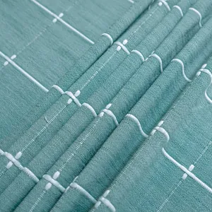 Makroaufnahme einer blaugrünen Tischdecke mit weiß gesticktem Gittermuster und Textur