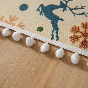 Primo piano di una tovaglia natalizia jacquard con motivo renna e bordo di pompon