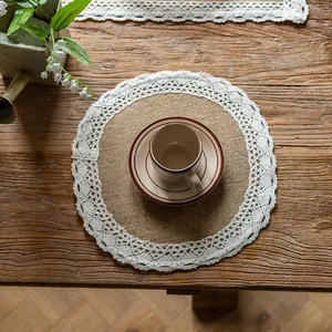 Round burlap placemat with white lace trim on a rustic wooden table with a coffee cup