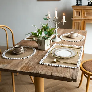 Farmhouse vintage burlap placemats with white pom-pom trim set on a rustic wooden table