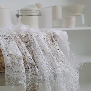 Detail van het delicate witte kant tafelkleed met elegant bloemmotief en fijne textuur