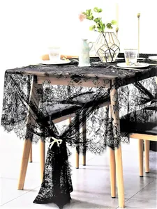 Intricate black floral lace tablecloth on a wooden table with elegant home decor