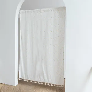 White fabric door curtain with yellow dot pattern and tassels hanging in an archway