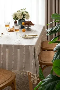 Detail of rustic cotton linen tablecloth with white embroidery and tassel trim