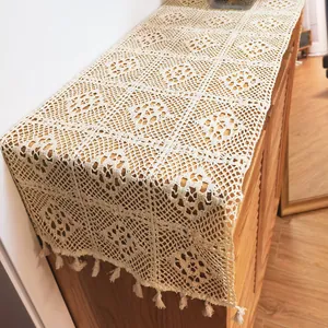 Close-up of vintage hollow-out crochet lace table runner with elegant tassel detail.