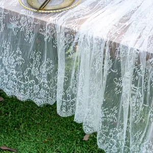 Detailed view of elegant white lace tablecloth with floral patterns and scalloped edges.