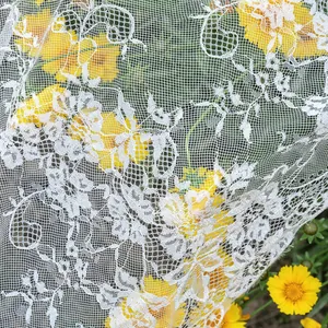 Detailopname van elegant wit bloemen kant tafelkleed over gele tuinbloemen in de zon