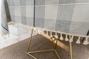 Detailansicht der grau karierten Tischdecke aus Baumwollleinen mit beigen Quastenfransen.