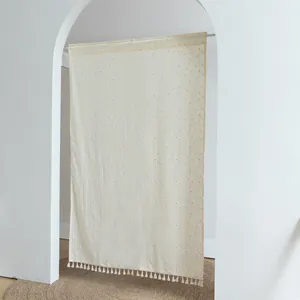 Minimalist white fabric door curtain with orange polka dots and tassels in an arched doorway