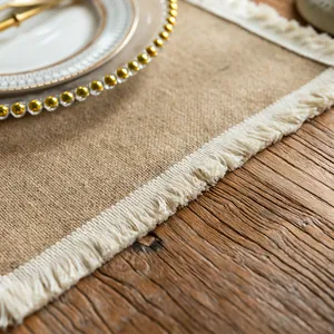 Close-up detail of a rustic jute placemat featuring off-white fringe on a wooden table