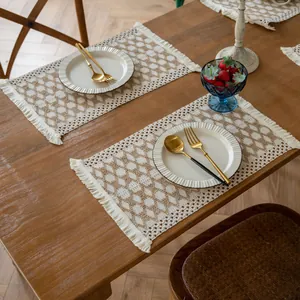 Close-up of farmhouse woven placemats with fringe tassels on a wooden table