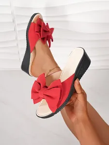 Sandales compensées en daim rouge avec un grand nœud et des semelles noires.