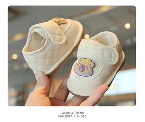 Dettaglio di scarpe primi passi per neonati color crema con simpatico orsetto