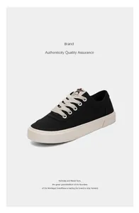 Nahaufnahme von schwarzen Low-Top-Canvas-Sneakern mit weißen Schnürsenkeln auf weiß