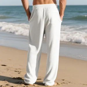 Back view of men's white textured ribbed wide-leg trousers on a scenic sunny beach.