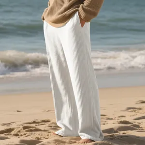 Detailed view of men's white ribbed jacquard wide-leg pants on a beach