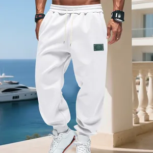 Macro view of white loose-fit fleece joggers with a minimalist logo patch on the leg.