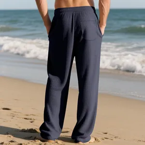 Back view of men's navy blue textured wide-leg casual pants worn on a sunny beach.