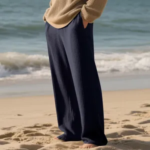 Close-up of men's ribbed striped wide-leg pants shown in a relaxing beach setting